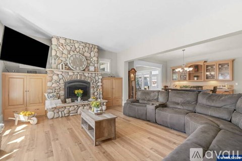 A living room with a stone fireplace and grey couches.