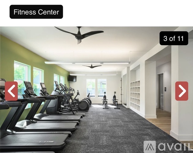 A fitness center with treadmills, elliptical machines, and a fan.
