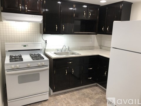 A kitchen with black cabinets and a white refrigerator.