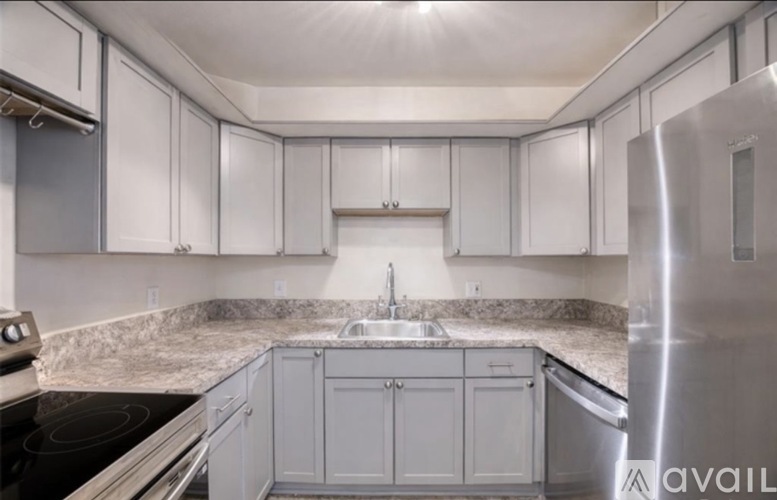 A kitchen with white cabinets and a marble countertop.