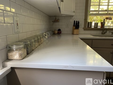 A kitchen counter with a row of glass jars filled with grains.