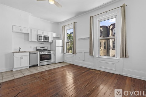 A kitchen with white cabinets and a wooden floor.