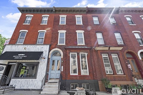 A red brick building with a black awning and a blue door.