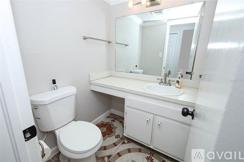 A white bathroom with a toilet, sink, and mirror.