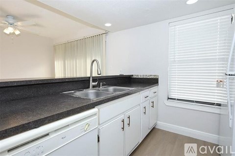 A kitchen with white cabinets and a black countertop.