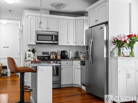 A kitchen with white cabinets and a stainless steel refrigerator.