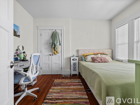 A bedroom with a bed, a chair, and a rug.