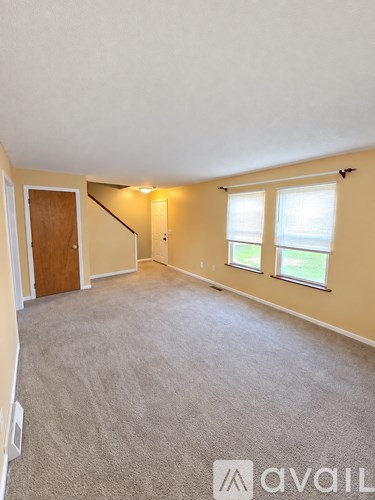 A carpeted room with a window and a door.