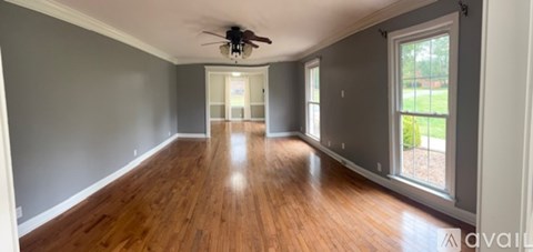 A spacious room with wooden floors and a ceiling fan.
