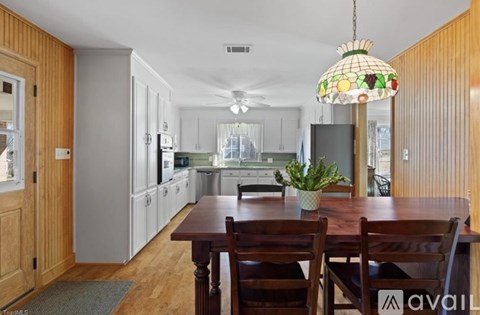 A kitchen with a table and chairs in the foreground and a staircase in the background.