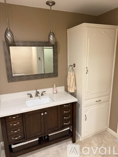 A bathroom with a sink, mirror, and cabinet.