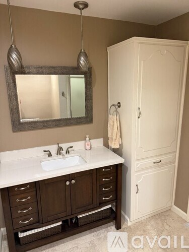 A bathroom with a sink, mirror, and cabinet.