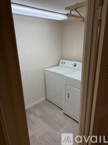 A small white washing machine sits in a narrow room.