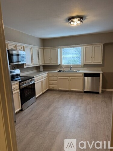 A kitchen with white cabinets and a wooden floor.