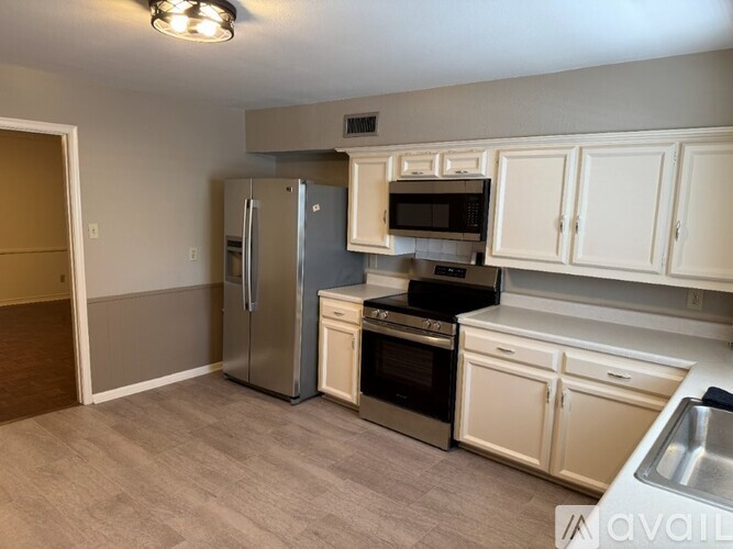 A kitchen with a refrigerator, oven, microwave, and cabinets.
