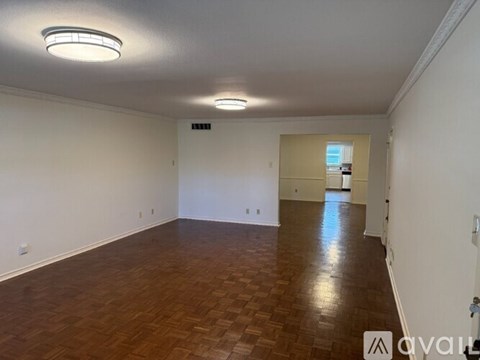 A spacious room with wooden flooring and white walls.