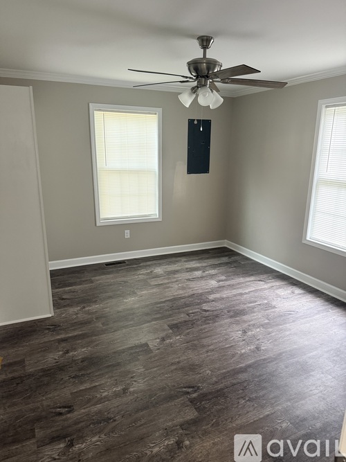 A room with a ceiling fan and wood flooring.