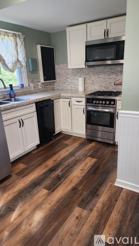 A kitchen with wooden floors and white cabinets.