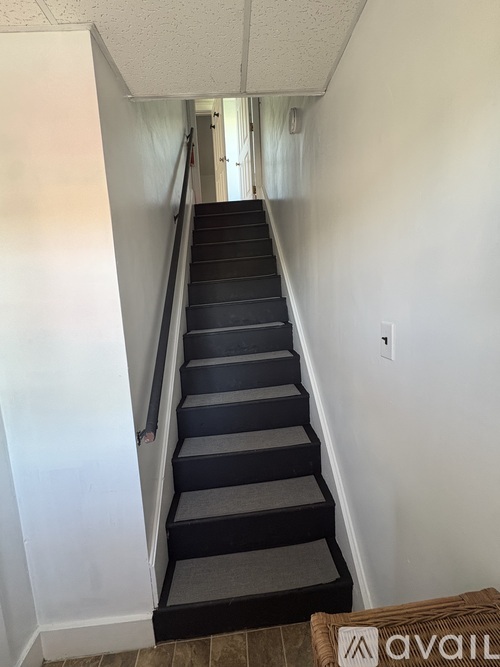 A staircase with a carpeted runner and a metal handrail.