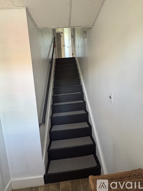 A staircase with a carpeted runner and a metal handrail.