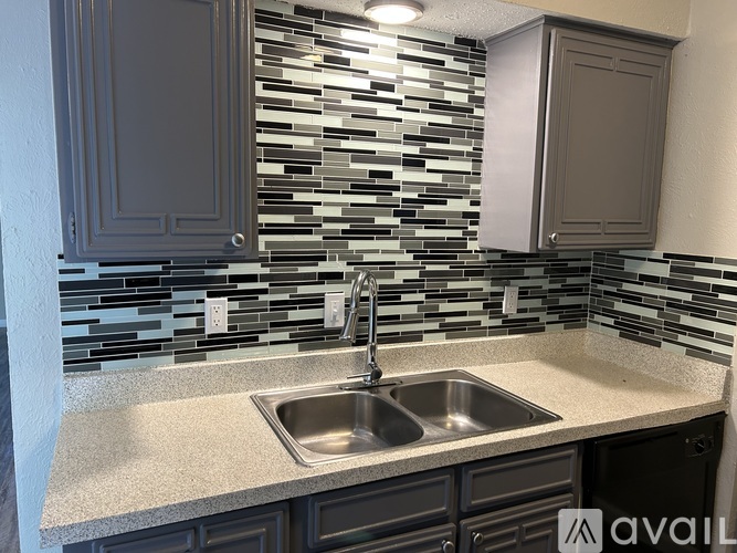 A kitchen with a sink and a backsplash of tiles.