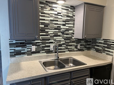 A kitchen with a sink and a backsplash of tiles.
