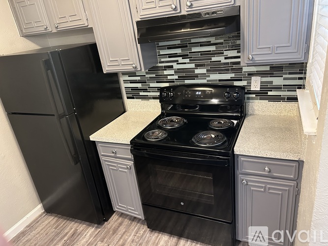 A kitchen with a black refrigerator and a black stove top oven.