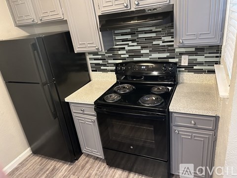 A kitchen with a black refrigerator and a black stove top oven.