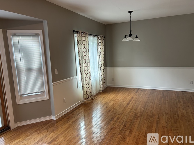 A room with wooden floors and a window with curtains.