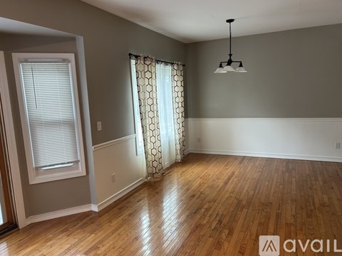 A room with wooden floors and a window with curtains.