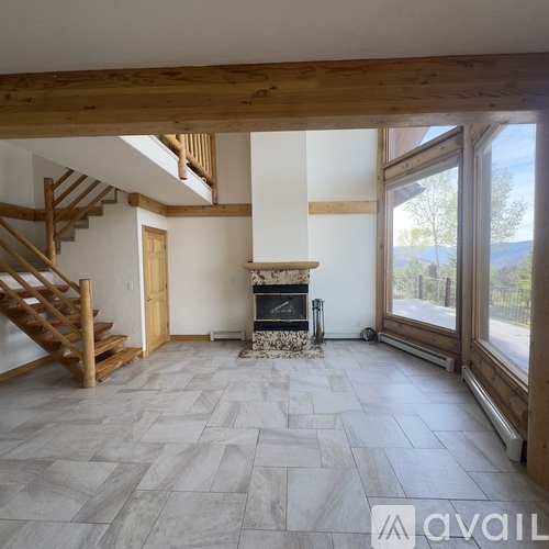 A living room with a fireplace and a staircase.