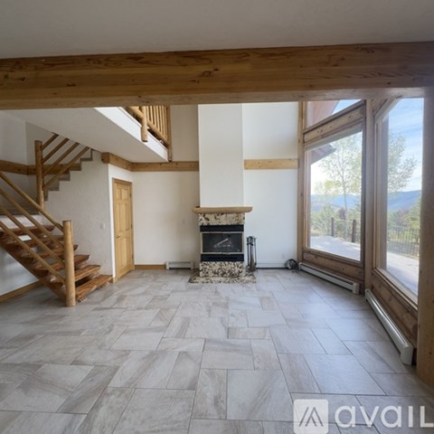 A living room with a fireplace and a staircase.