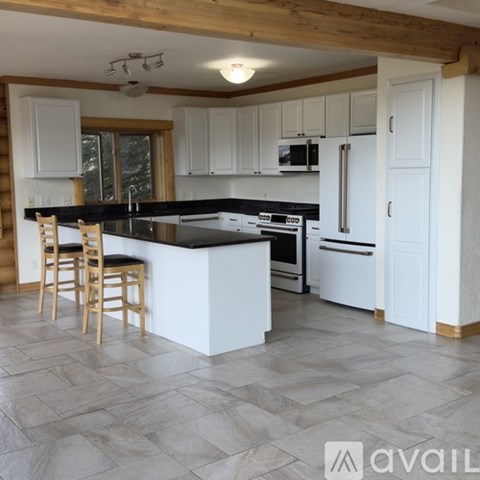 A kitchen with white cabinets and a black countertop.