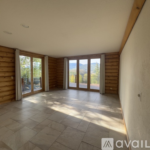 A spacious room with tiled flooring and large windows.