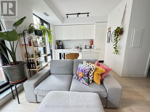 A grey couch with colorful pillows sits in a bright living room.