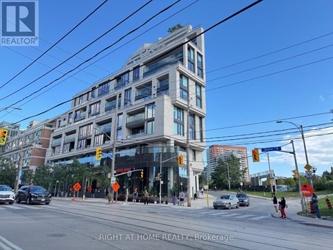 A street view of a city with a building in the background and a car driving on the road.