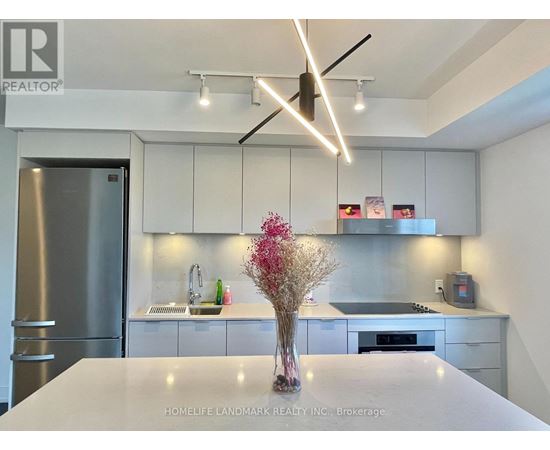 A modern kitchen with a white countertop and stainless steel appliances.