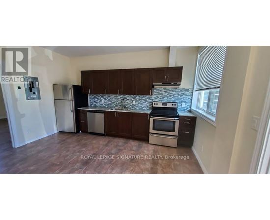 A kitchen with a refrigerator, stove, and cabinets.
