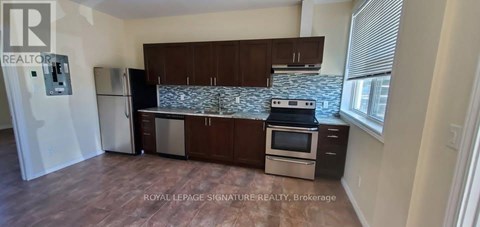 A kitchen with a refrigerator, stove, and cabinets.