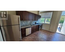 A kitchen with a refrigerator, cabinets, and a window.