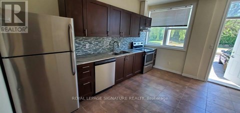 A kitchen with a refrigerator, cabinets, and a window.