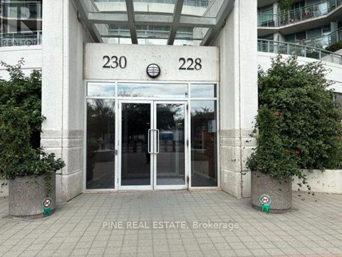 The image shows the entrance to a building with the numbers 230 and 228 on the wall above the glass doors.