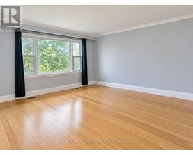 A room with wooden flooring and a window with black curtains.