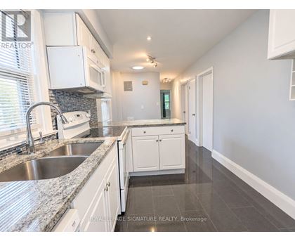 A kitchen with white cabinets and a marble countertop.