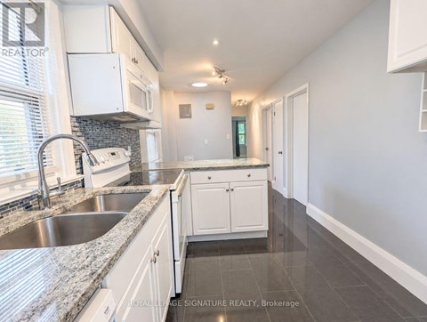 A kitchen with white cabinets and a marble countertop.