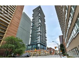 A tall building with a glass facade stands in the middle of a city street.