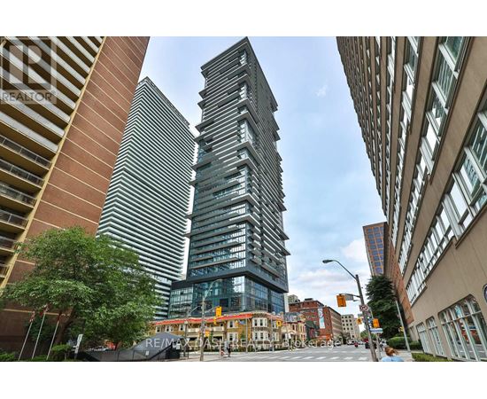 A tall building with a glass facade stands in the middle of a city street.