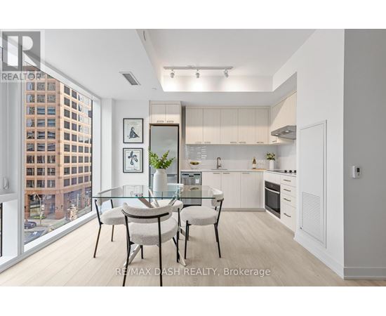 A modern kitchen with a glass table and chairs, a fridge, a microwave, and a stove.