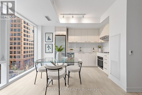 A modern kitchen with a glass table and chairs, a fridge, a microwave, and a stove.