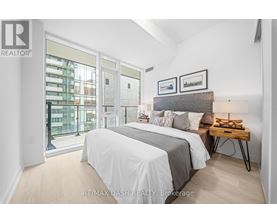 A bedroom with a large bed and a view of a city street through the window.